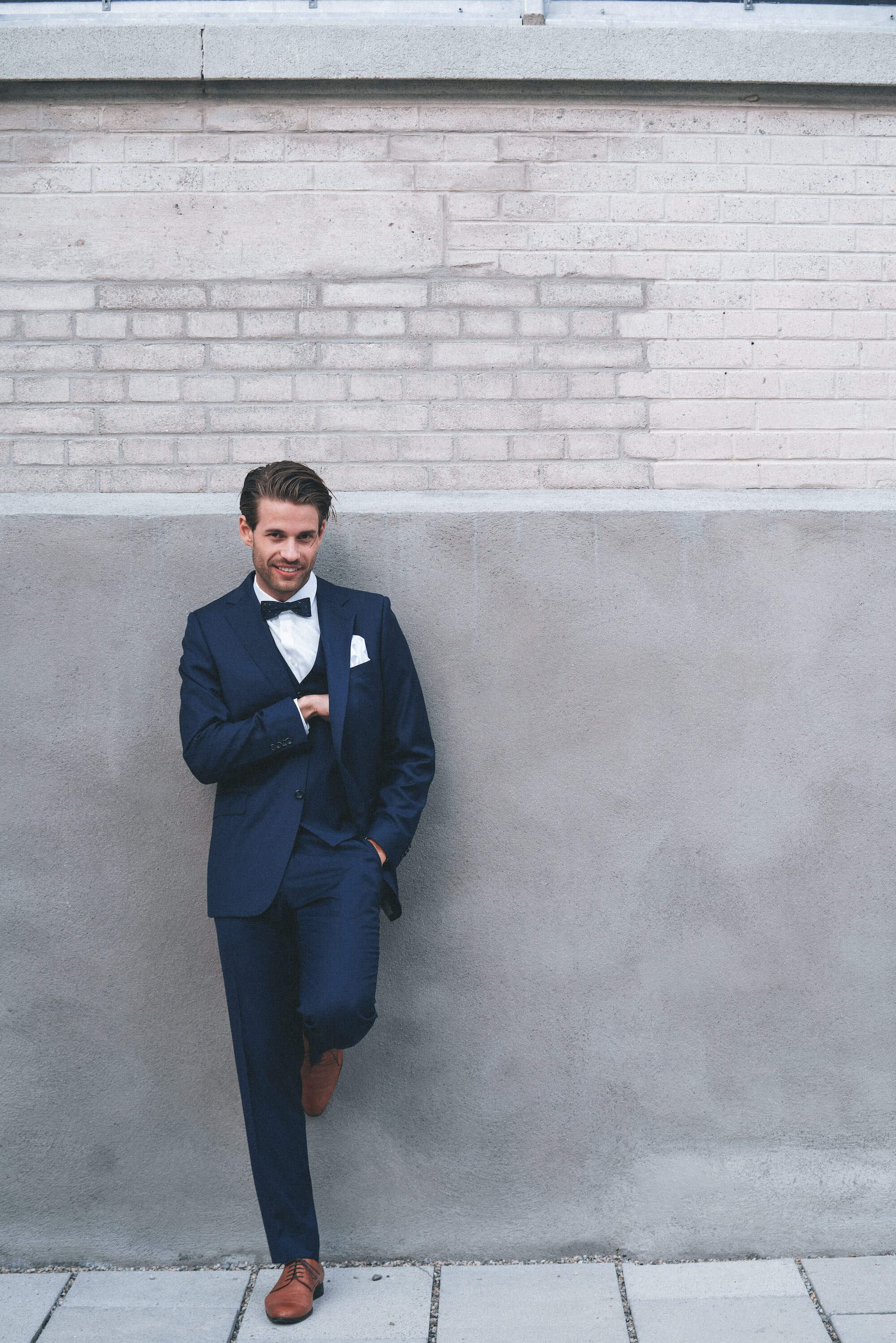 Junger Mann im Anzug steht an der Wand